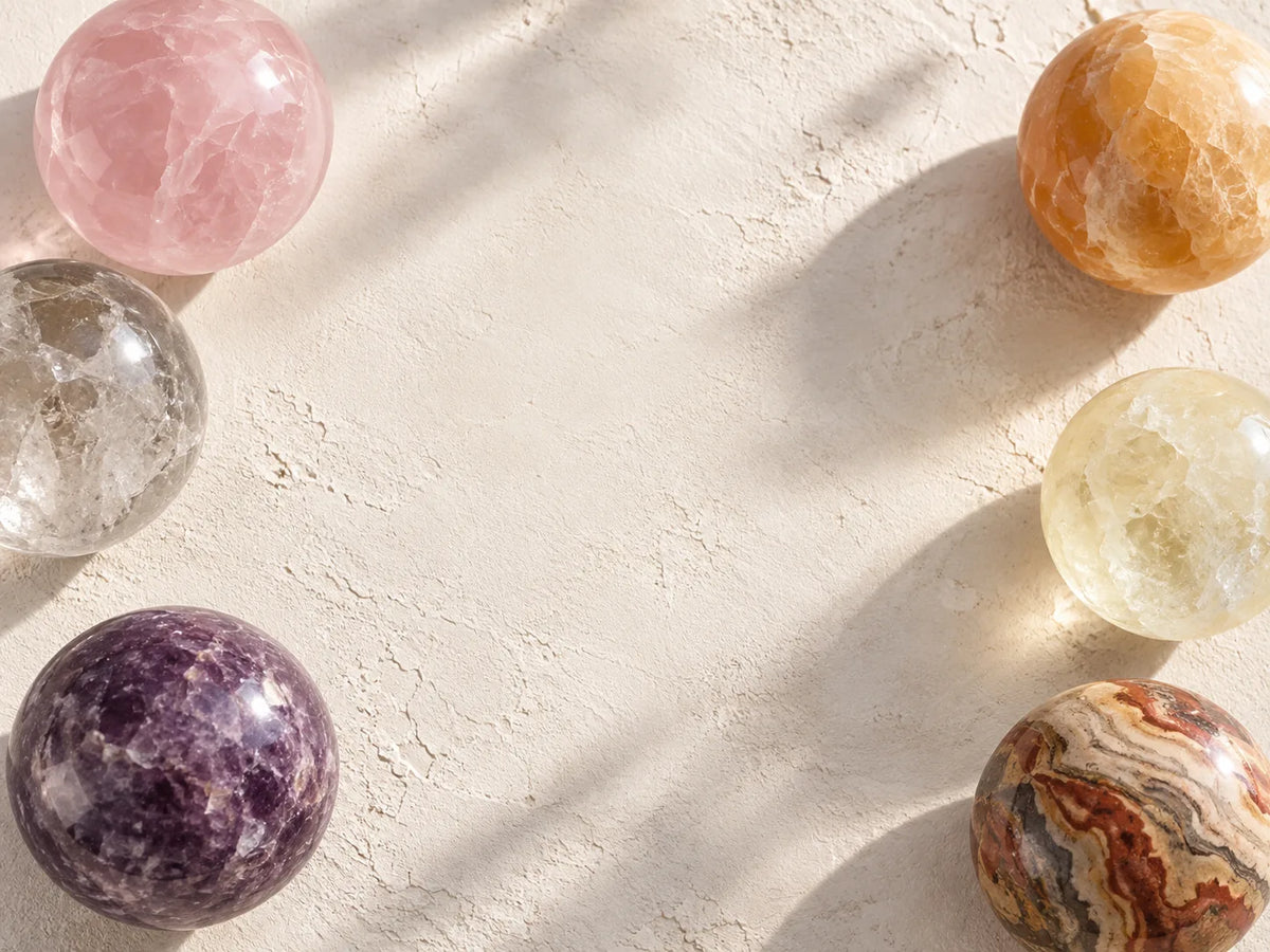 Polished gemstone spheres arranged on a warm natural stone background